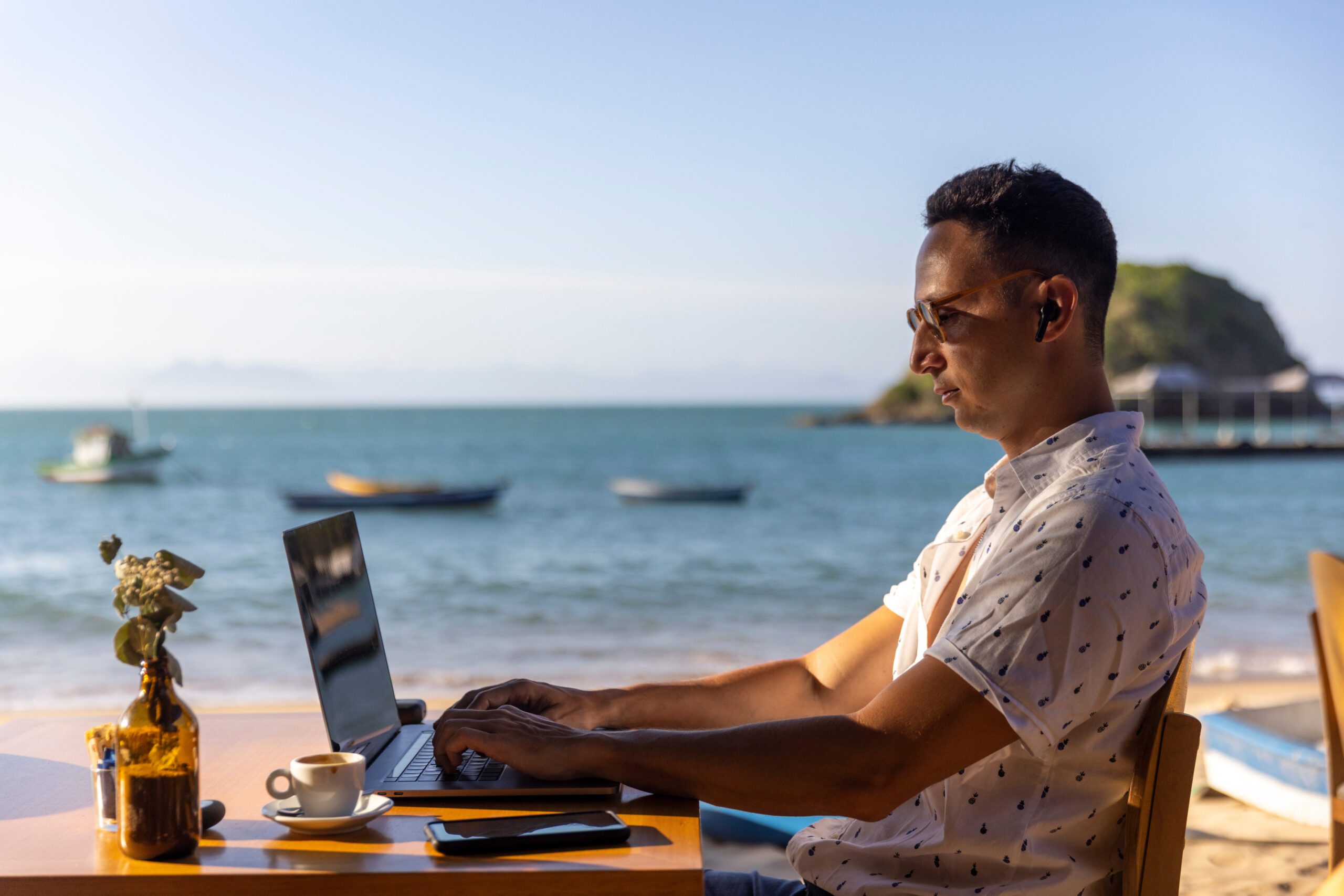 Man Using Laptop At Beach Cafe